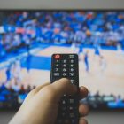 Basketball game on TV with hand holding a Remote