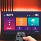 Hand holding remote pointing at Smart TV