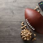 Football, Remote and bowl of pistachio on grey background