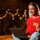 woman holiday shopping with on laptop with credit card in hand