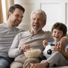Father and Sons on the couch watching TV laughing