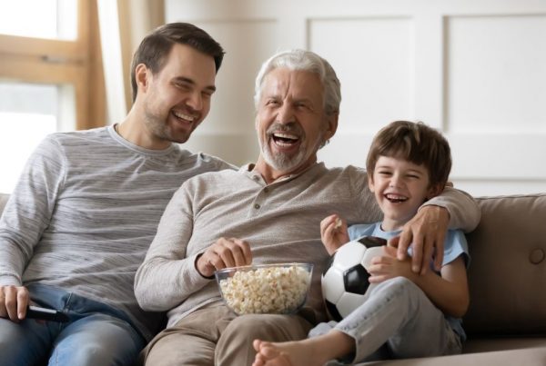 Father and Sons on the couch watching TV laughing